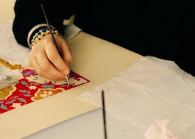 Close-up of an artist painting a colorful, intricate design on paper.