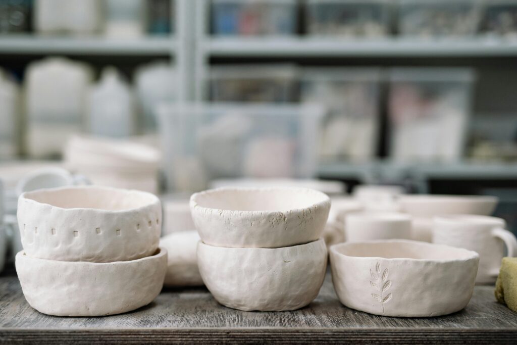 A collection of handmade unglazed ceramic bowls displayed in a pottery studio.