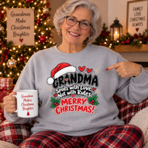 Smiling grandmother wearing a Christmas sweatshirt with playful Grandma typography, Santa hat and festive details.