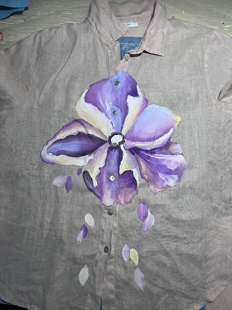 Early hand-painted clothing experiment with purple flower on gray fabric