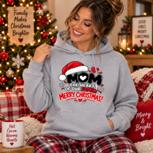 Woman wearing a festive Mom Christmas hoodie featuring “The Heart of Our Family” typography with Santa hat details.
